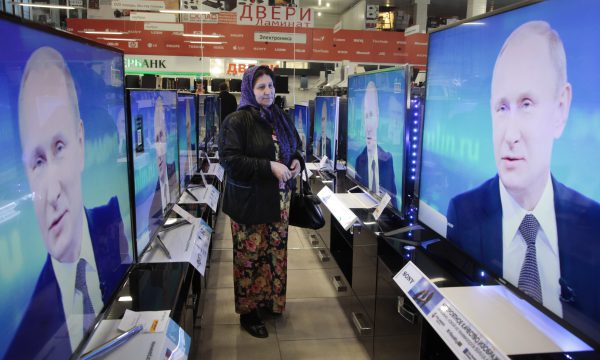 A Chechen woman looks at a TV screen with Russian President Vladimir Putin.