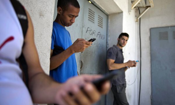 three young people look at their phones