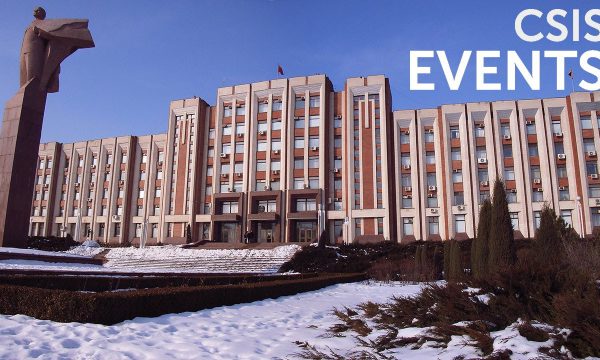 A large sand-colored building and light snow in the foreground