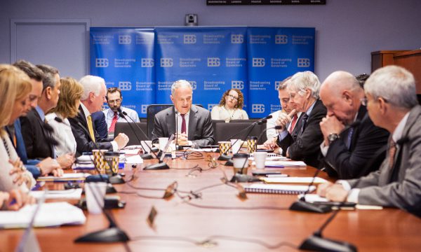 Several senior executives meet at a conference table