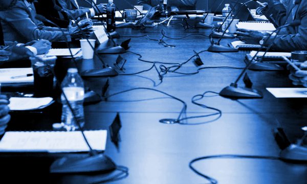 group of people sit around a board table, the focus is on their hands