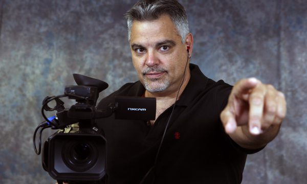 man standing next to camera, pointing at viewer