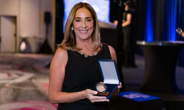 woman in black dress holds an award medal